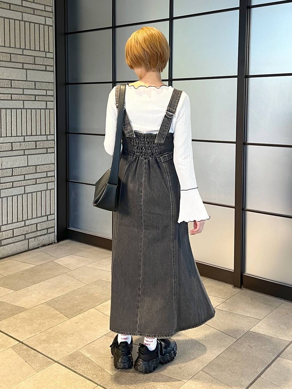 ブラック系のデニムジャケット、ブラック系のジャンパースカート、ブラック系のバレエシューズを着用したレディースの冬コーディネートの6枚目の写真
