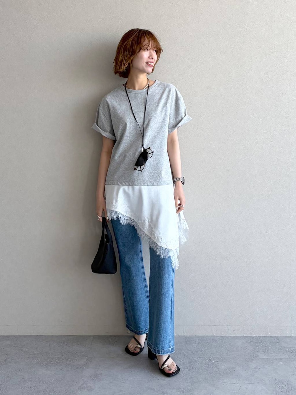 ブルー系のデニムパンツ、グレー系のTシャツ/カットソー、ブラック系のショルダーバッグを着用したレディースの春コーディネートの4枚目の写真