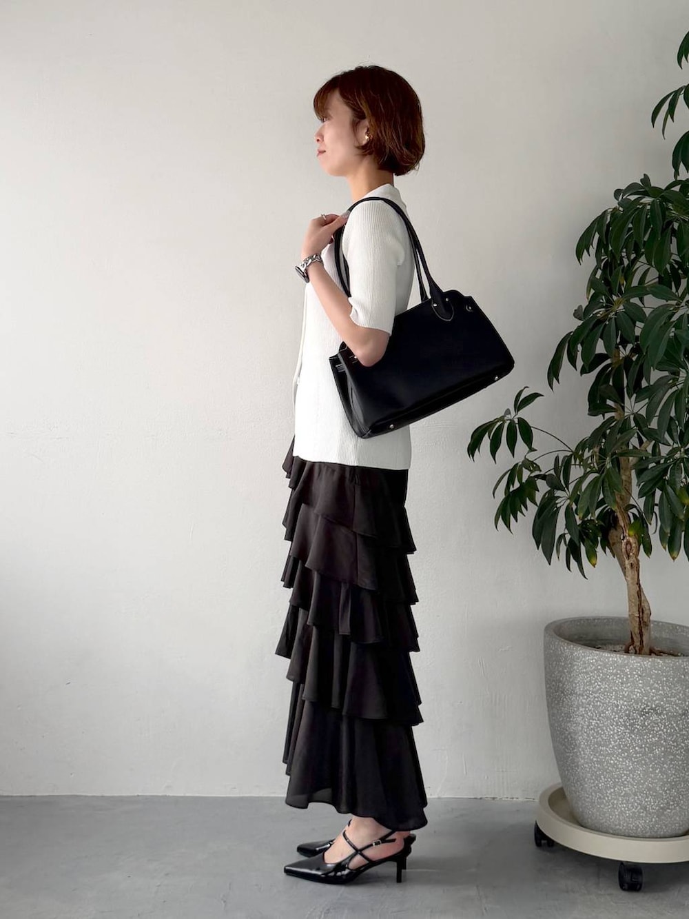 ブラック系のサンダル、ホワイト系のカーディガン/ボレロ、ブラック系のスカートを着用したレディースの春コーディネートの2枚目の写真