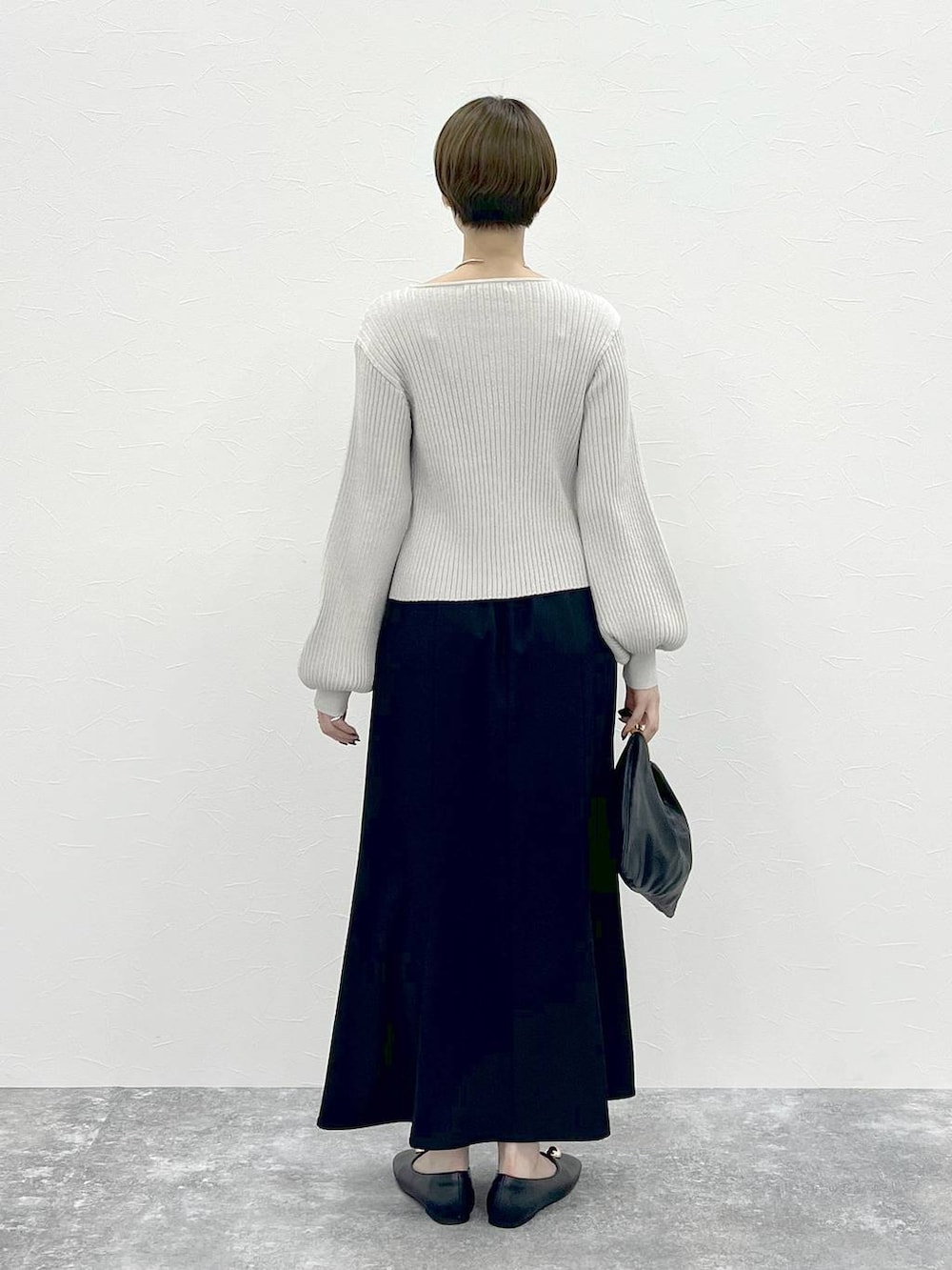 ブラック系のスカート、ブラック系のハンドバッグ、ホワイト系のカーディガン/ボレロを着用したレディースの秋コーディネートの3枚目の写真