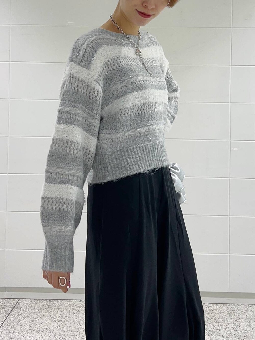 シルバー系のショルダーバッグ、ブラック系のブーツ、ブラック系のスカートを着用したレディースの冬コーディネートの6枚目の写真