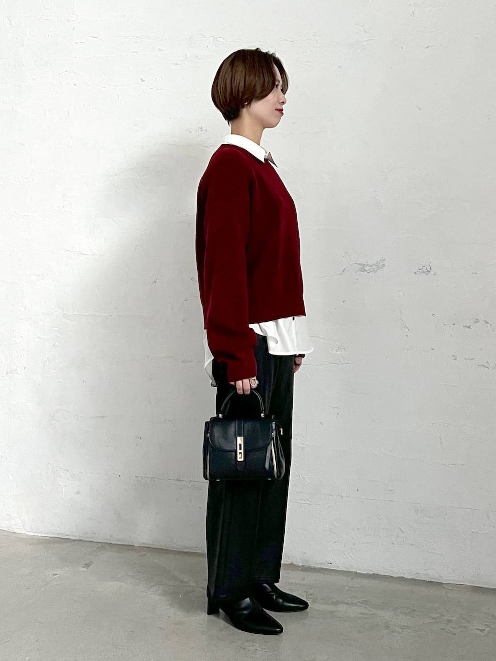 レッド系のニット/セーター、ブラック系のブーツ、ブラック系のスラックスを着用したレディースの冬コーディネートの2枚目の写真