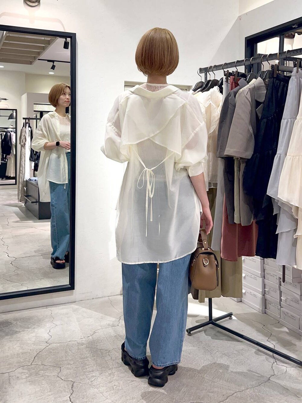 ブルー系のデニムパンツ、ブラック系のサンダル、ブラウン系のショルダーバッグを着用したレディースの夏コーディネートの2枚目の写真