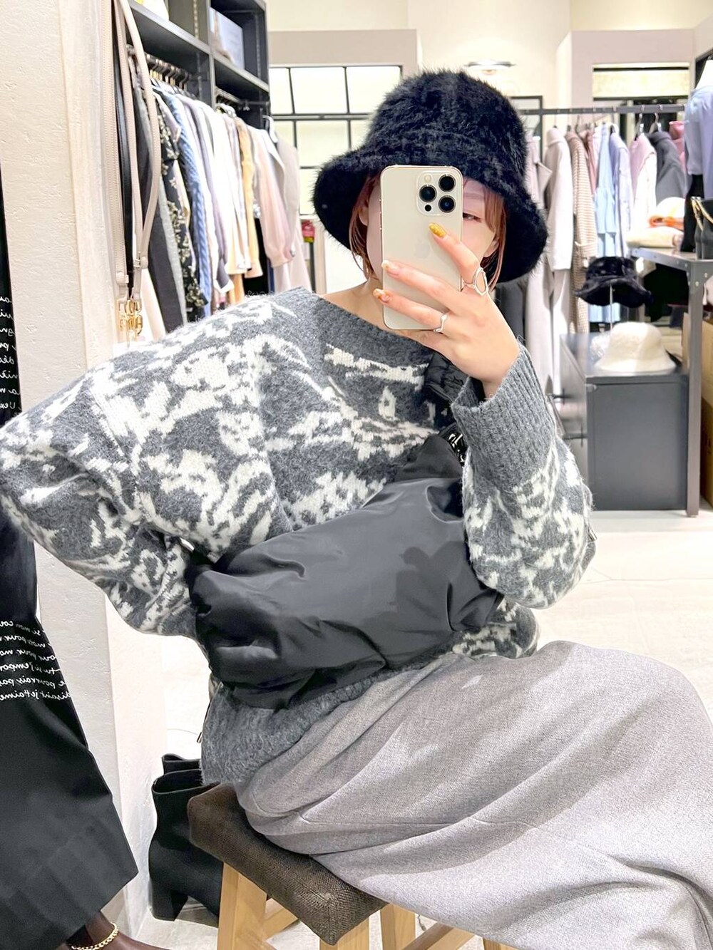 ブラック系のハンドバッグ、ブラック系のブーツ、グレー系のニット/セーターを着用したレディースの冬コーディネートの4枚目の写真