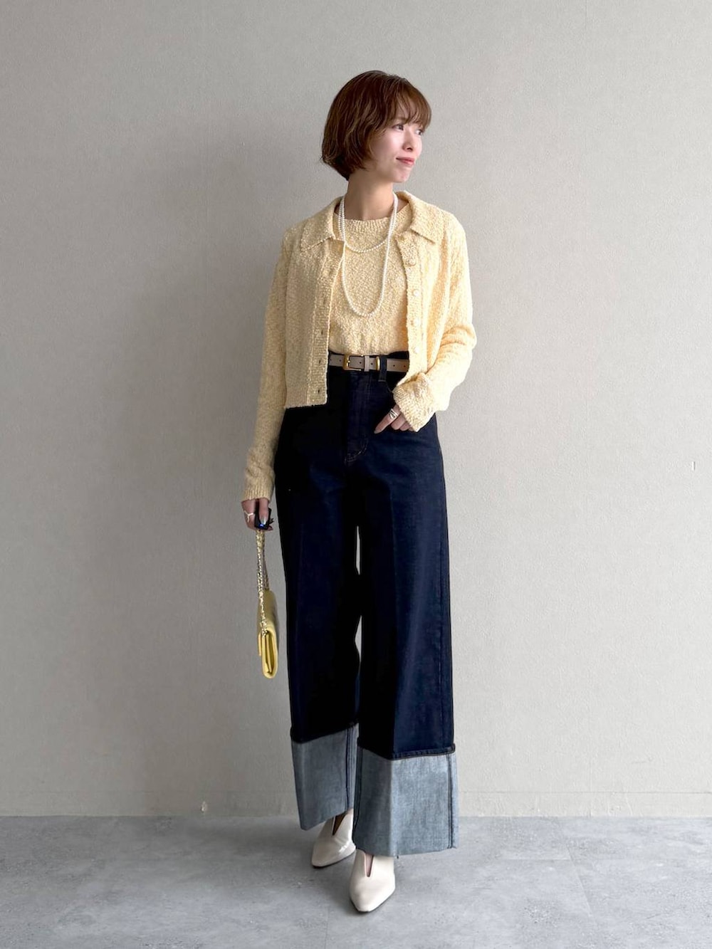 ホワイト系のサンダル、ブラウン系のブルゾン、イエロー系のカーディガン/ボレロを着用したレディースの春コーディネートの5枚目の写真