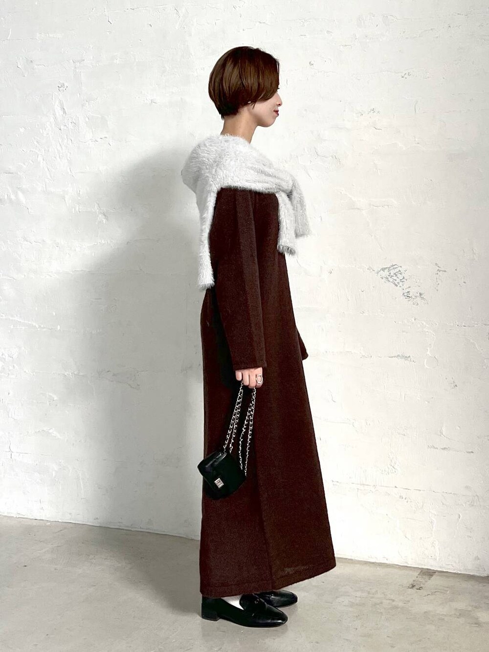 ブラック系のローファー、グレー系のニット/セーター、ブラック系のショルダーバッグを着用したレディースの冬コーディネートの2枚目の写真