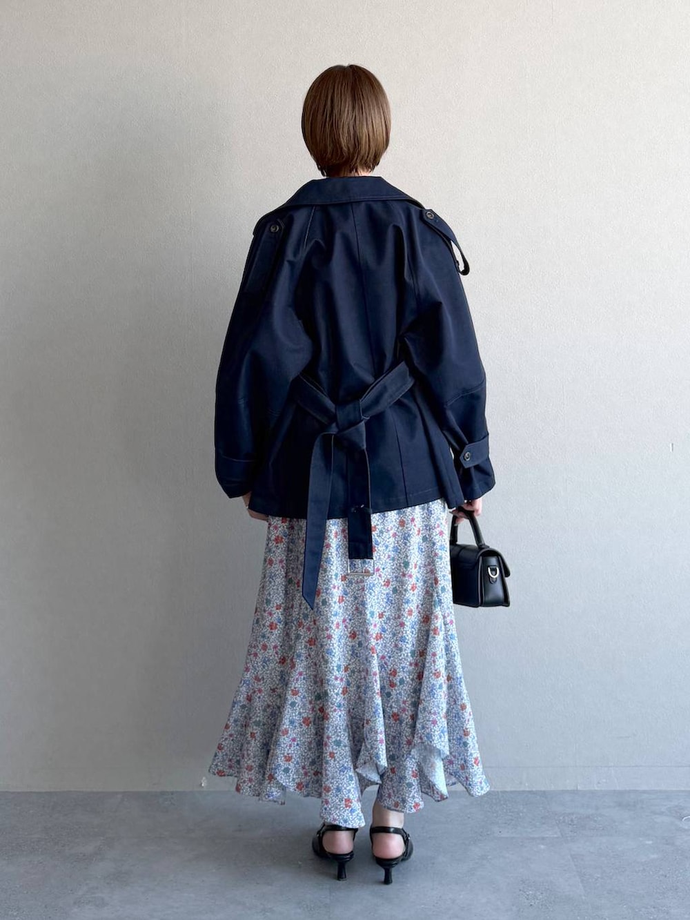 ブラック系のショルダーバッグ、ブラック系のサンダル、ブルー系のトレンチコートを着用したレディースの冬コーディネートの3枚目の写真