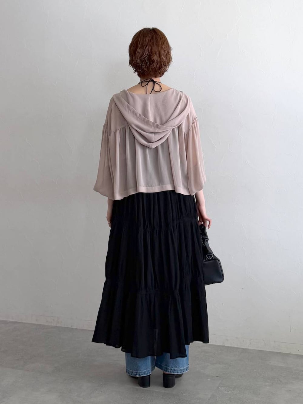 ベージュ系のパーカー、ブルー系のデニムパンツ、ブラック系のショルダーバッグを着用したレディースの夏コーディネートの3枚目の写真