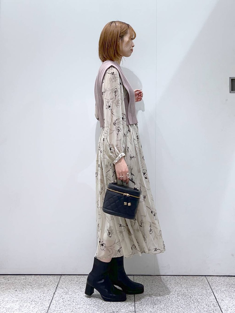 ブルー系のノーカラーコート、ブラック系のブーツ、ベージュ系のワンピースを着用したレディースの秋コーディネートの5枚目の写真