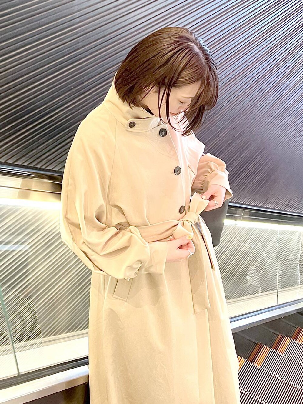 ブラック系のハンドバッグ、ブラック系のパンプス、ベージュ系のトレンチコートを着用したレディースの春コーディネートの3枚目の写真