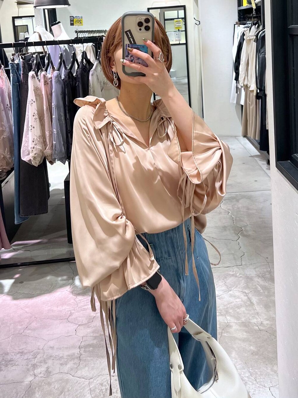 ブラウン系のパンプス、ブルー系のデニムパンツ、ホワイト系のショルダーバッグを着用したレディースの春コーディネートの2枚目の写真