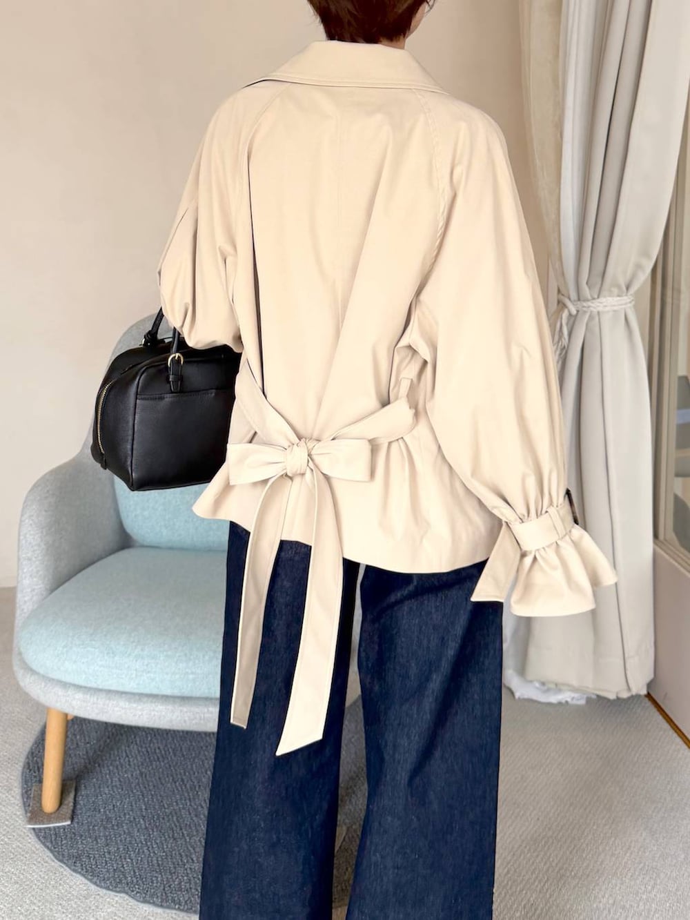 ブルー系のデニムパンツ、ベージュ系のトレンチコート、ブラック系のハンドバッグを着用したレディースの秋コーディネートの5枚目の写真