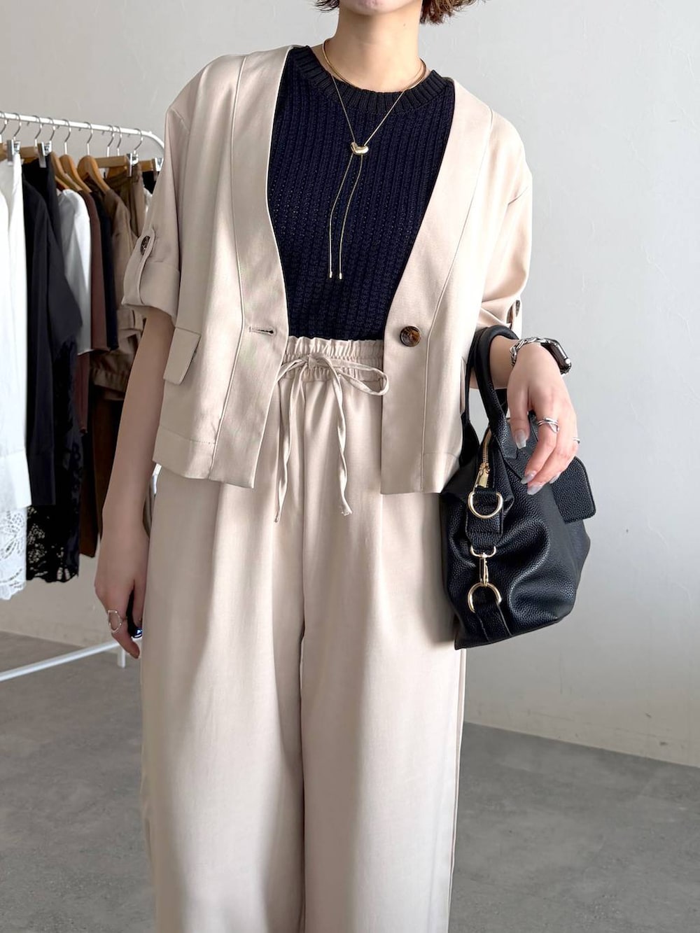 ブラック系のボストンバッグ、ブラック系のサンダル、ホワイト系のセットアップを着用したレディースの春コーディネートの4枚目の写真