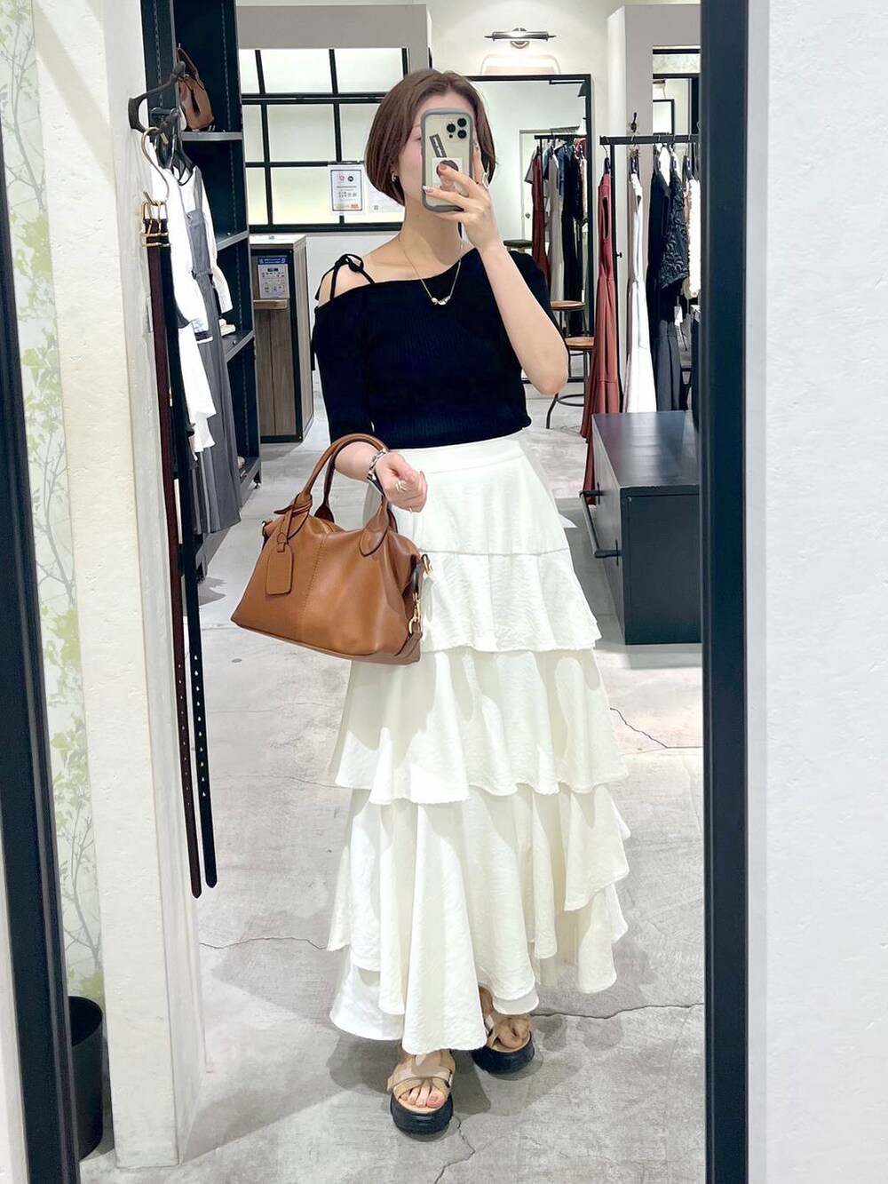 ホワイト系のスカート、ベージュ系のサンダル、ブラック系のニット/セーターを着用したレディースの春コーディネートの4枚目の写真