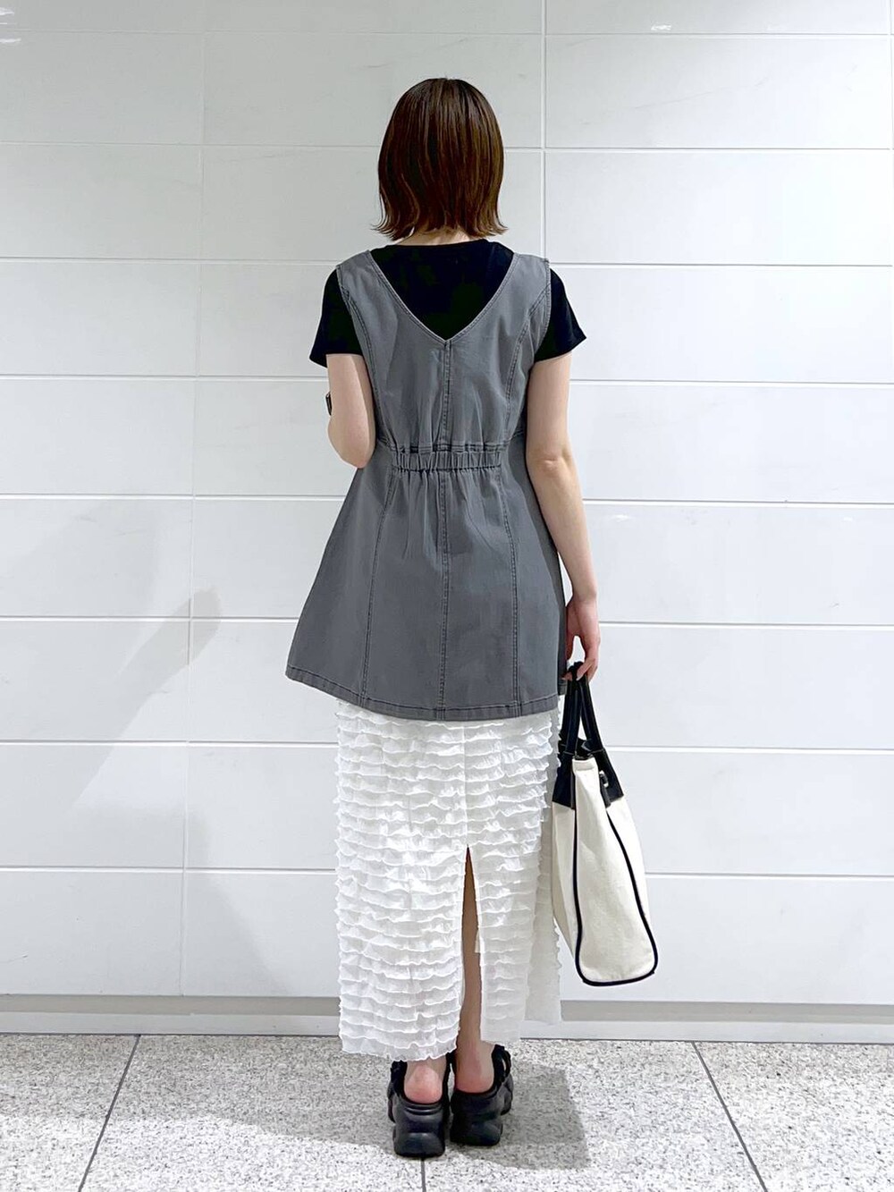 ブラック系のトートバッグ、ブラック系のTシャツ/カットソー、ブラック系のサンダルを着用したレディースの春コーディネートの4枚目の写真