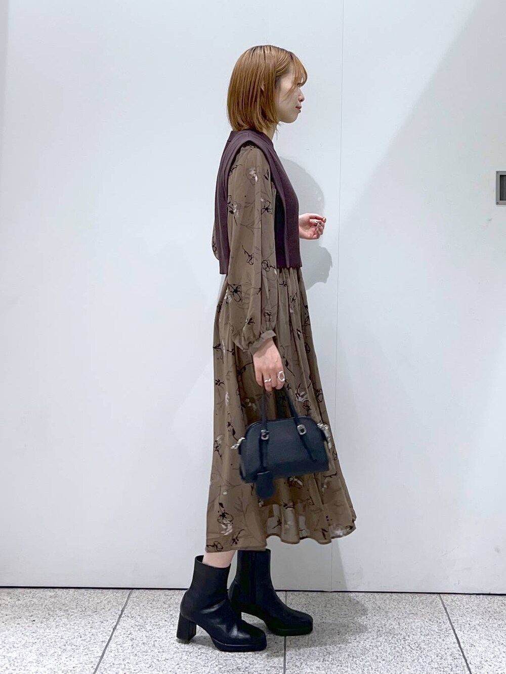 ホワイト系のチェスターコート、ブラック系のボストンバッグ、ブラック系のブーツを着用したレディースの秋コーディネートの5枚目の写真