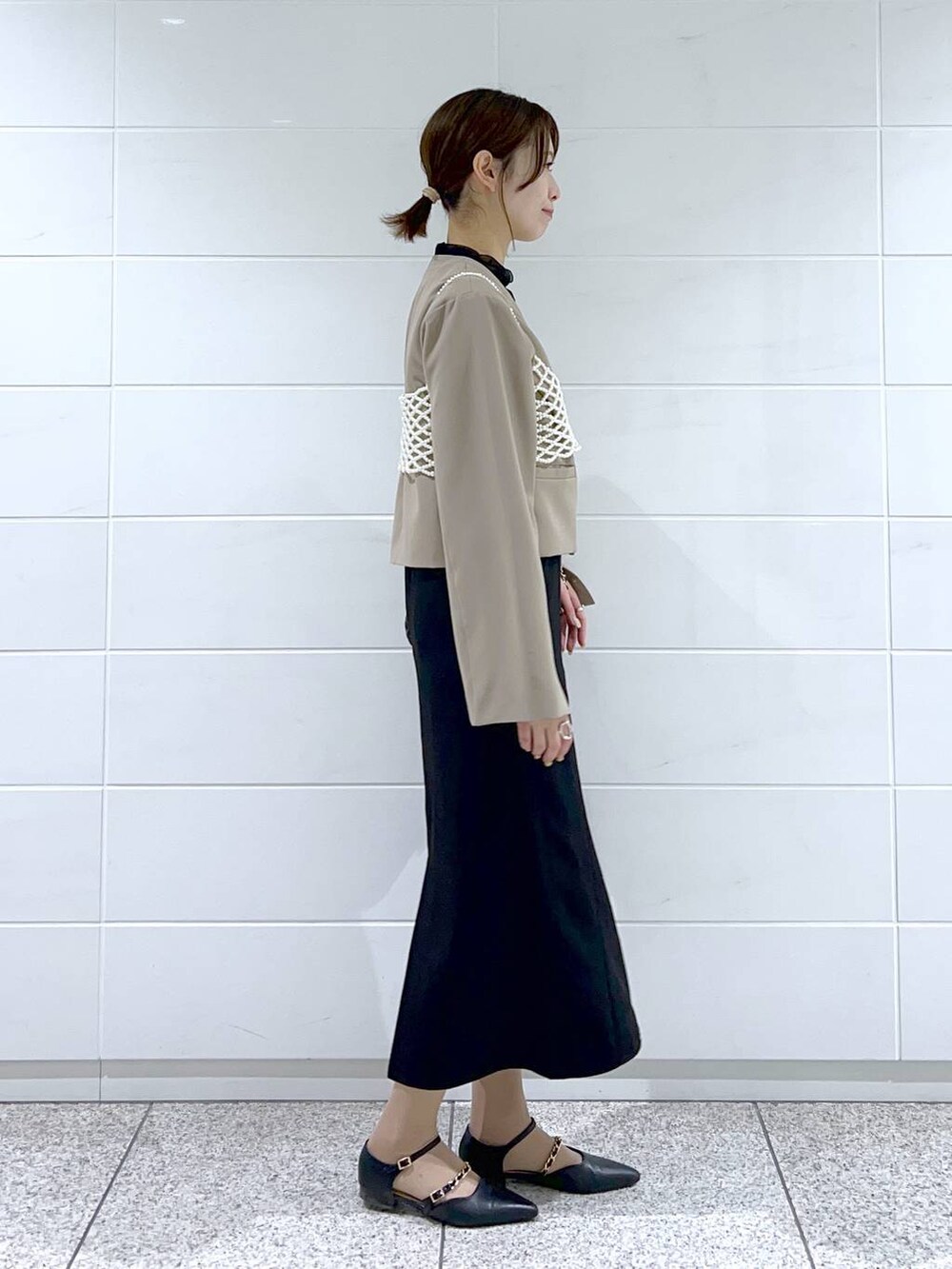 ブラック系のドレス、ブラック系のショルダーバッグ、ブラック系のパンプスを着用したレディースの春コーディネートの2枚目の写真