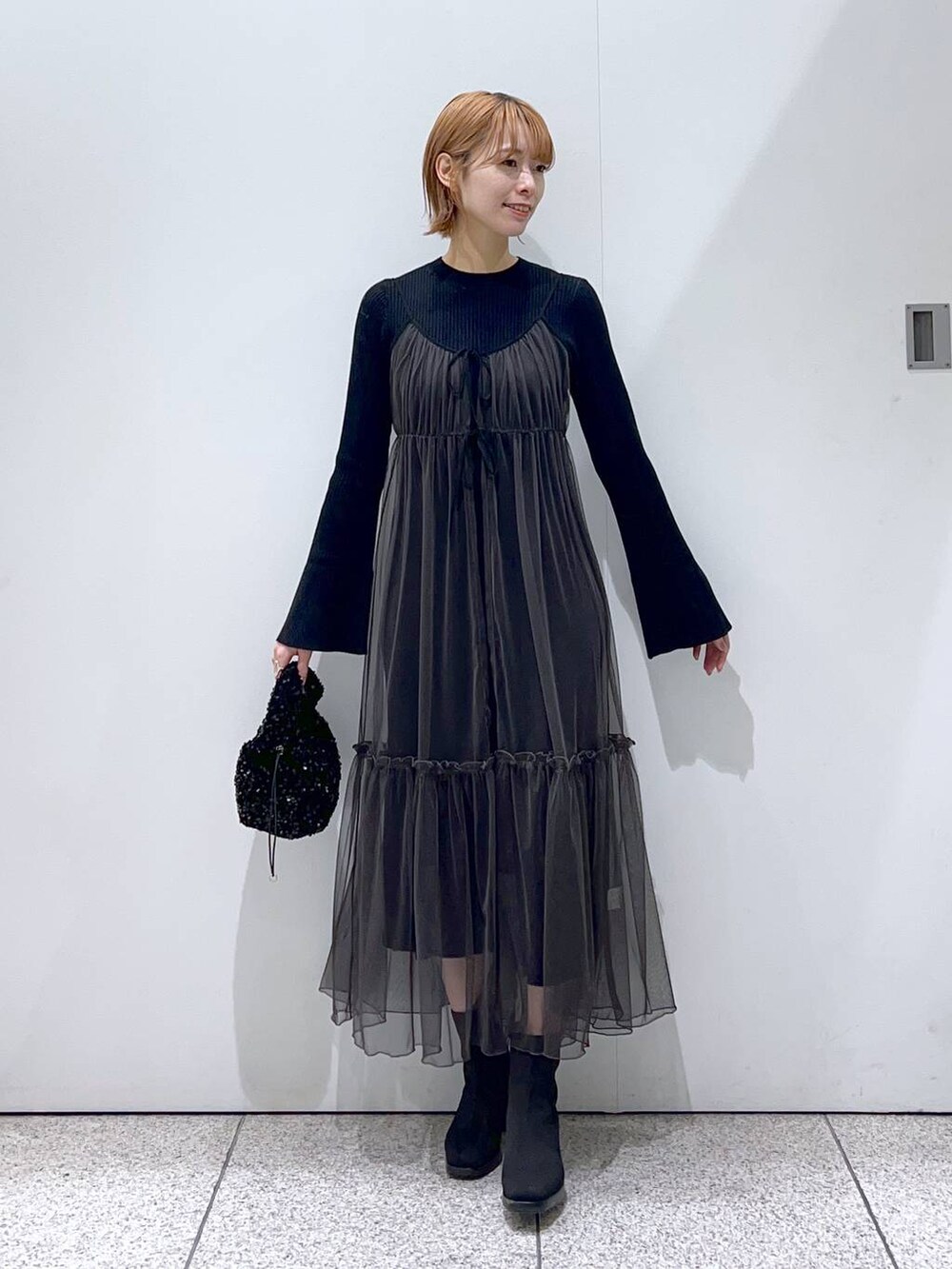 ホワイト系のチェスターコート、ブラック系のブーツ、ブラック系のハンドバッグを着用したレディースの冬コーディネートの4枚目の写真