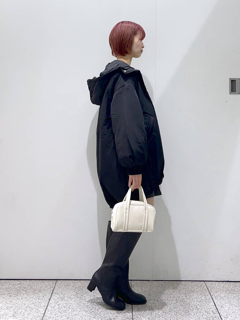 ブラック系のブルゾン、ホワイト系のボストンバッグ、ブラック系のブーツを着用したレディースの秋コーディネートの2枚目の写真