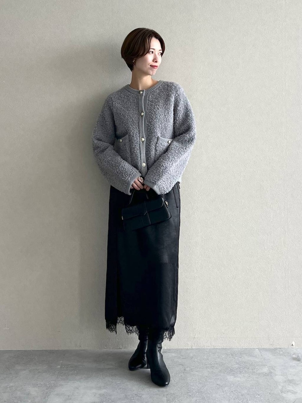 グレー系のカーディガン/ボレロ、ブラック系のブーツ、ブラック系のスカートを着用したレディースの秋コーディネートの5枚目の写真