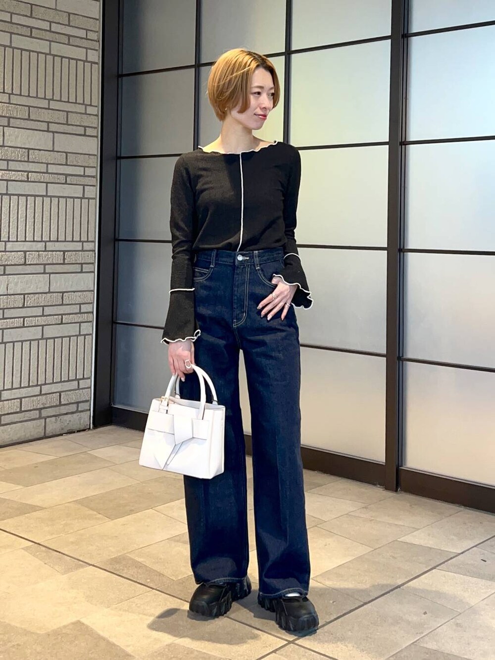 ホワイト系のブルゾン、ホワイト系のショルダーバッグ、ブルー系のスラックスを着用したレディースの冬コーディネートの4枚目の写真