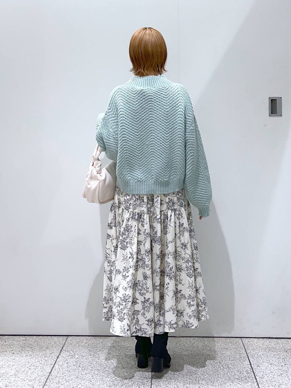 ブラック系のブーツ、ホワイト系のハンドバッグ、グリーン系のニット/セーターを着用したレディースの冬コーディネートの4枚目の写真