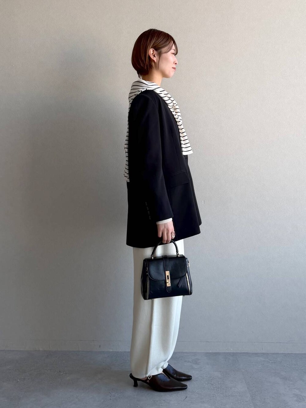 ブラック系のショルダーバッグ、ブラック系のサンダル、グレー系のニット/セーターを着用したレディースの冬コーディネートの2枚目の写真