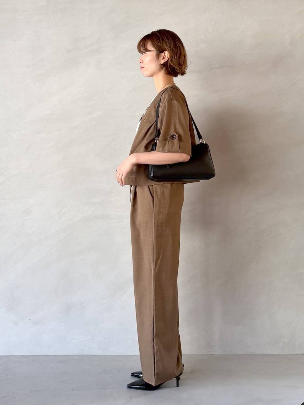 ブラック系のサンダル、ブラック系のショルダーバッグ、ブラウン系のセットアップを着用したレディースの春コーディネートの2枚目の写真