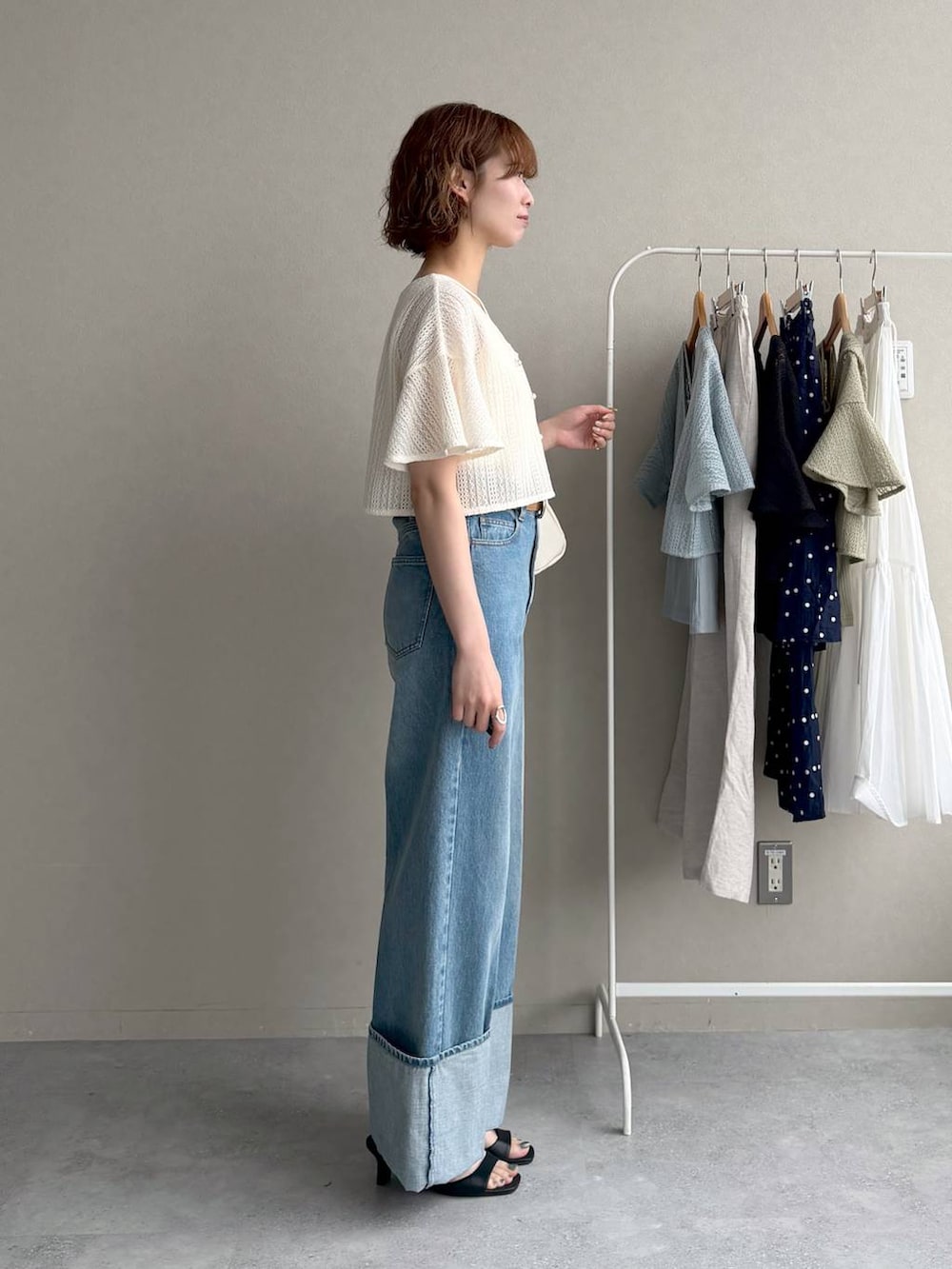 ホワイト系のカーディガン/ボレロ、ブルー系のデニムパンツ、ブラック系のサンダルを着用したレディースの春コーディネートの2枚目の写真