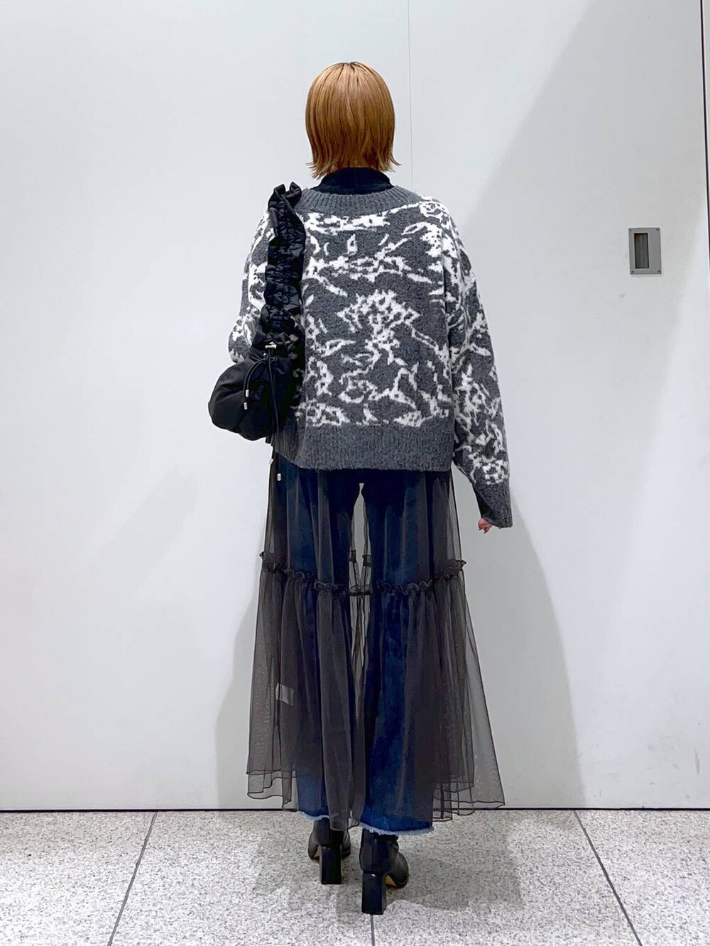 ブルー系のデニムパンツ、ブラック系のハンドバッグ、ブラック系のブーツを着用したレディースの冬コーディネートの3枚目の写真