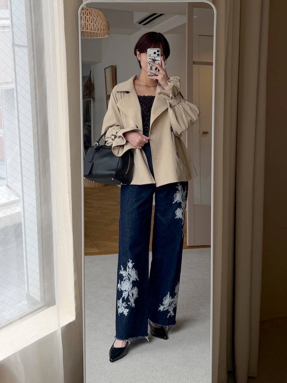 ブルー系のデニムパンツ、ベージュ系のトレンチコート、ブラック系のハンドバッグを着用したレディースの秋コーディネートの7枚目の写真