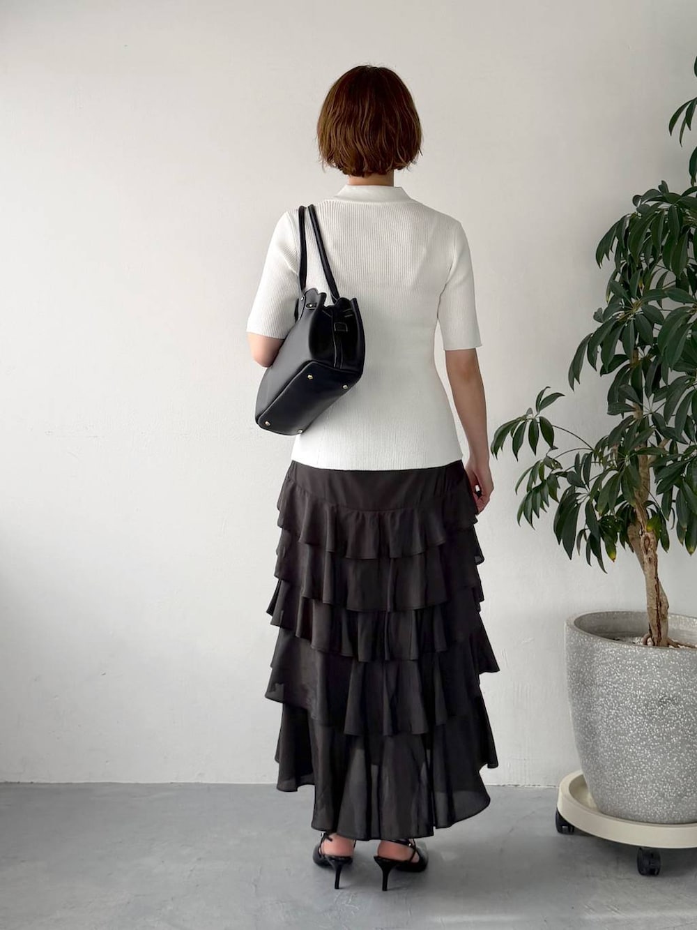 ブラック系のサンダル、ホワイト系のカーディガン/ボレロ、ブラック系のスカートを着用したレディースの春コーディネートの3枚目の写真