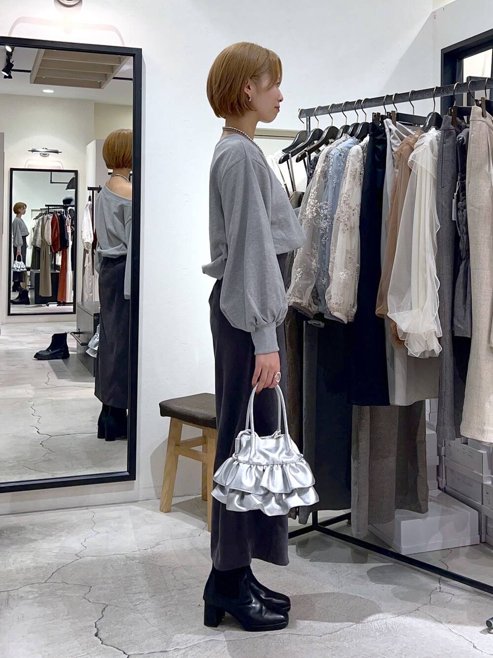 シルバー系のショルダーバッグ、ブラック系のブーツ、グレー系のスカートを着用したレディースの秋コーディネートの2枚目の写真