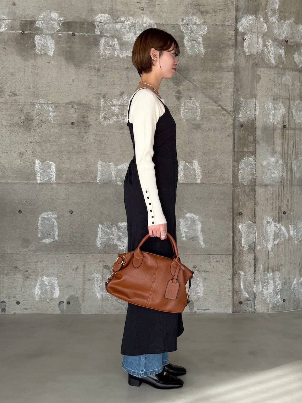 ブラウン系のボストンバッグ、ブラック系のローファー、ブルー系のデニムパンツを着用したレディースの冬コーディネートの2枚目の写真