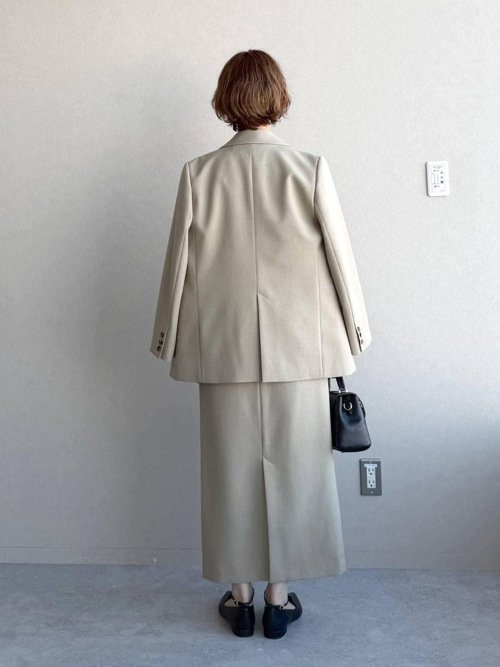 ブラック系のショルダーバッグ、ベージュ系のテーラードジャケット、ベージュ系のスカートを着用したレディースの冬コーディネートの3枚目の写真