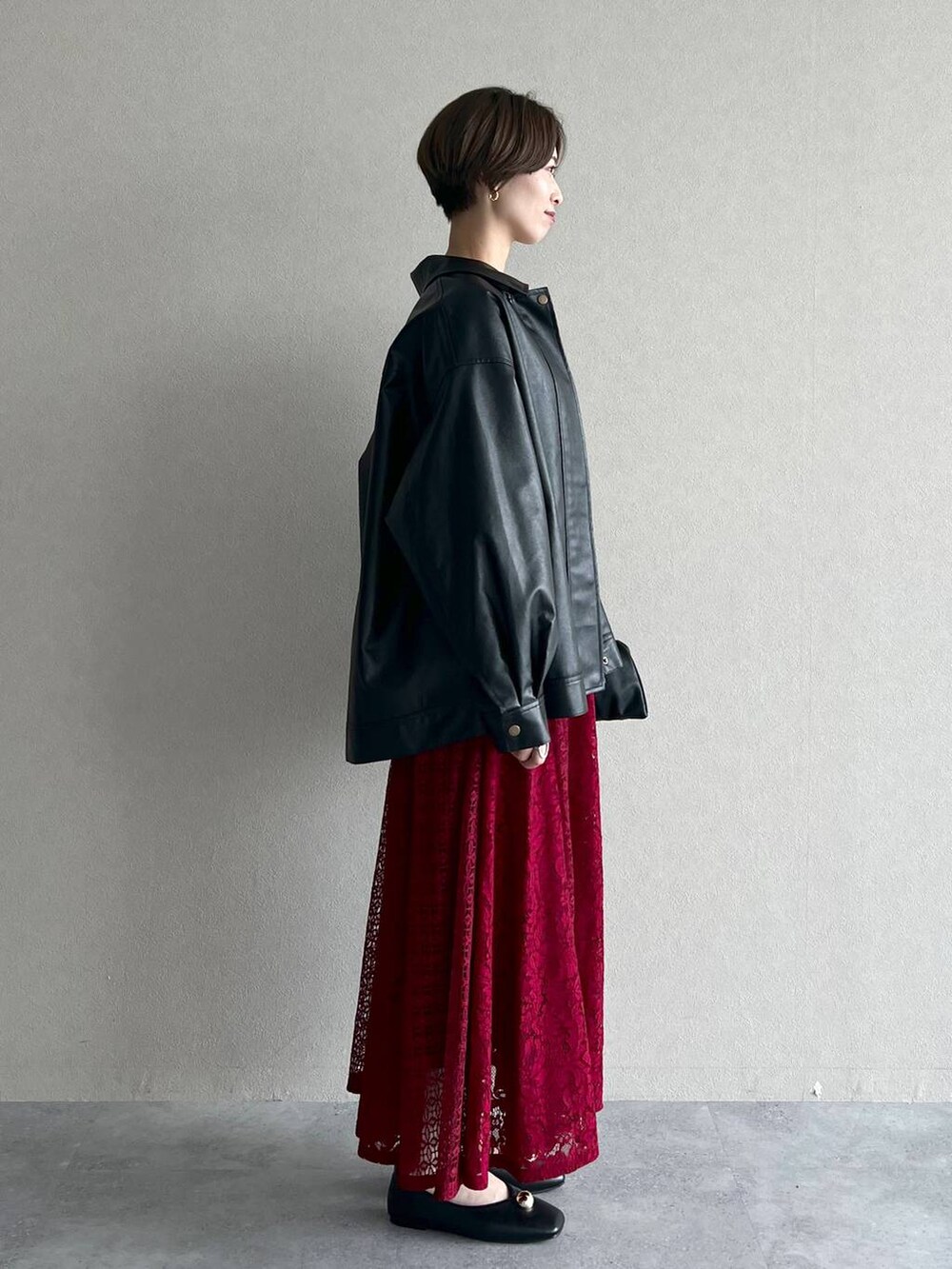 ブラック系のブルゾン、ブラック系のハンドバッグ、レッド系のワンピースを着用したレディースの秋コーディネートの2枚目の写真