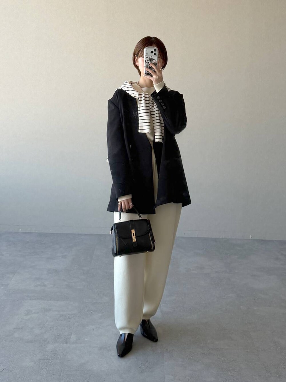 ブラック系のショルダーバッグ、ブラック系のサンダル、グレー系のニット/セーターを着用したレディースの冬コーディネートの7枚目の写真