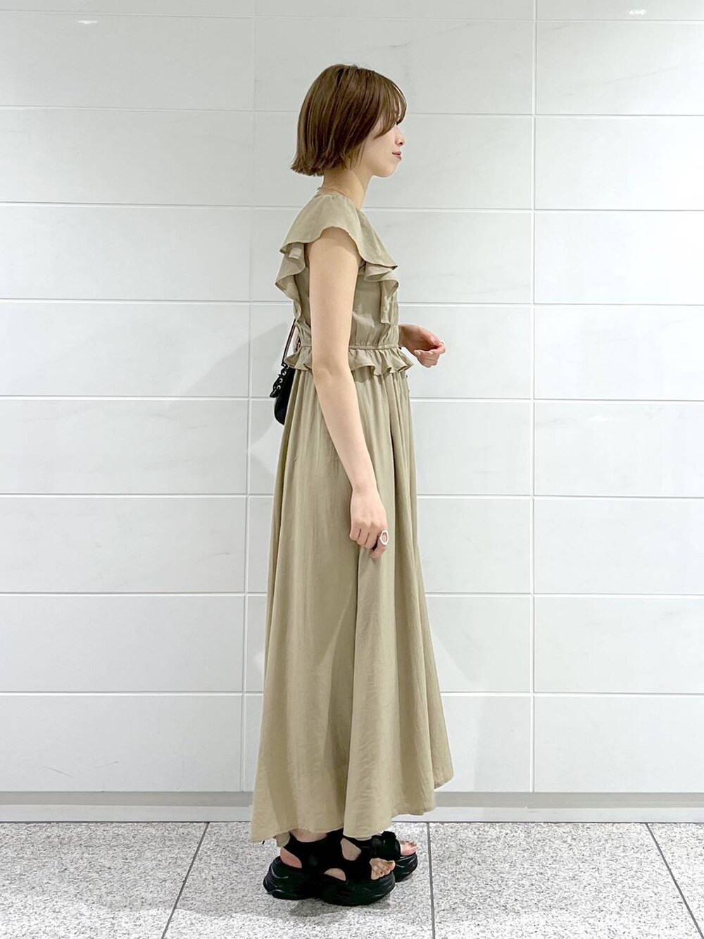 ブラック系のサンダル、ブラック系のショルダーバッグ、ベージュ系のワンピースを着用したレディースの春コーディネートの2枚目の写真