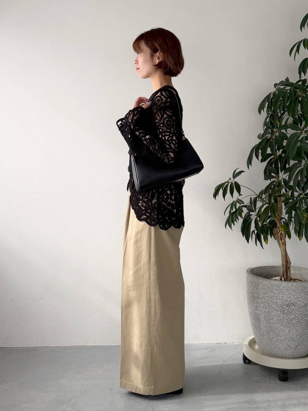 ブラック系のカーディガン/ボレロ、ブラック系のショルダーバッグ、ベージュ系のチノパンツを着用したレディースの春コーディネートの2枚目の写真