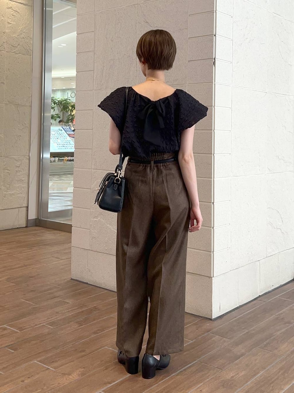 ブラック系のショルダーバッグ、ブラウン系のその他パンツ、ブラック系のドレスシューズを着用したレディースの夏コーディネートの3枚目の写真