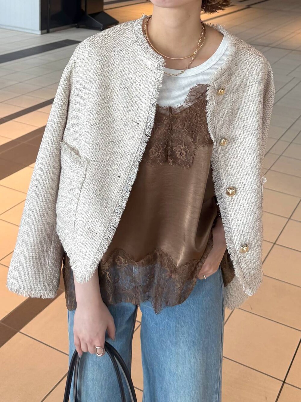 ブラック系のサンダル、ブラウン系のキャミソール、ホワイト系のノーカラージャケットを着用したレディースの春コーディネートの8枚目の写真