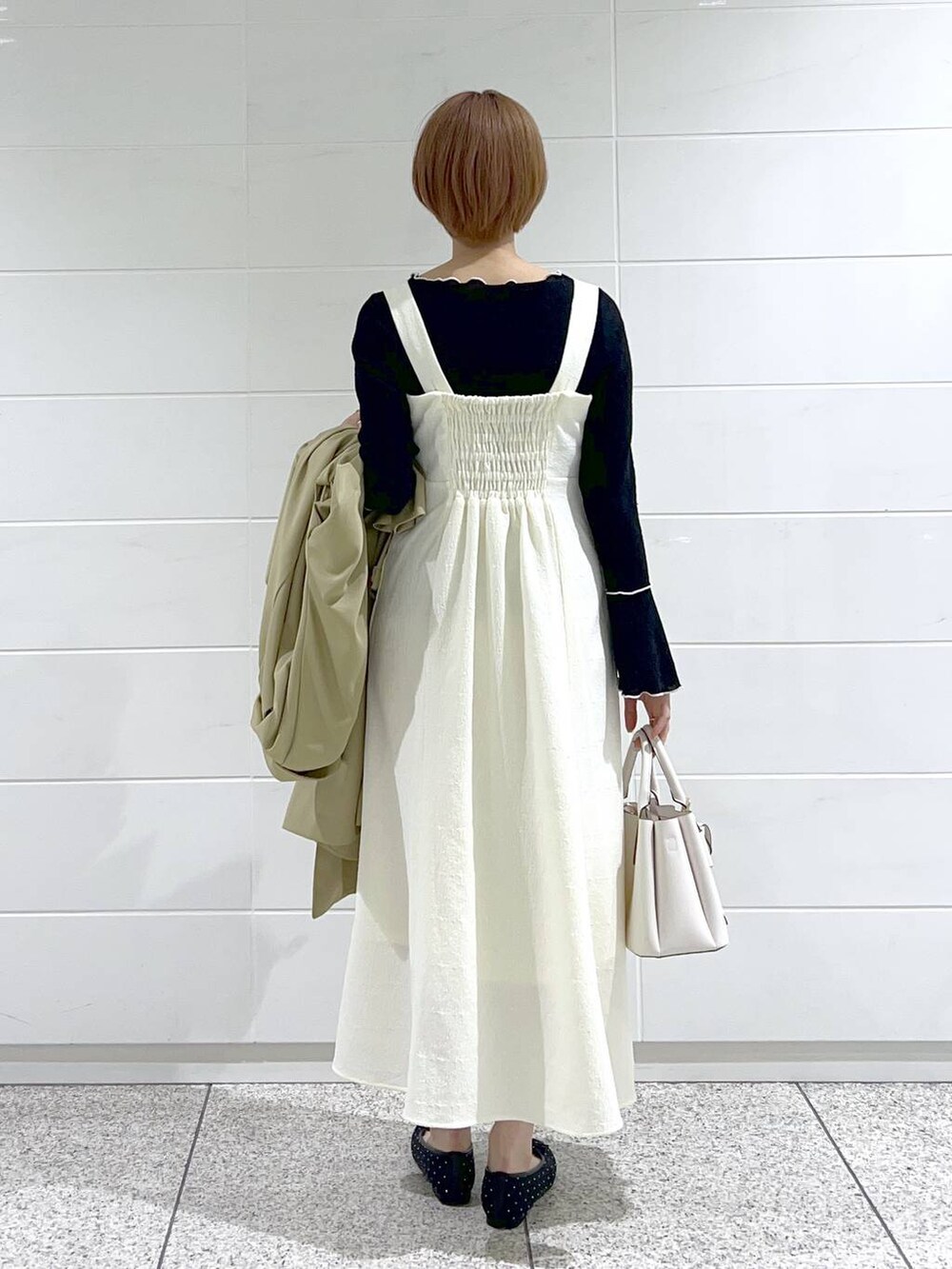 ホワイト系のショルダーバッグ、ベージュ系のトレンチコート、ブラック系のバレエシューズを着用したレディースの春コーディネートの6枚目の写真