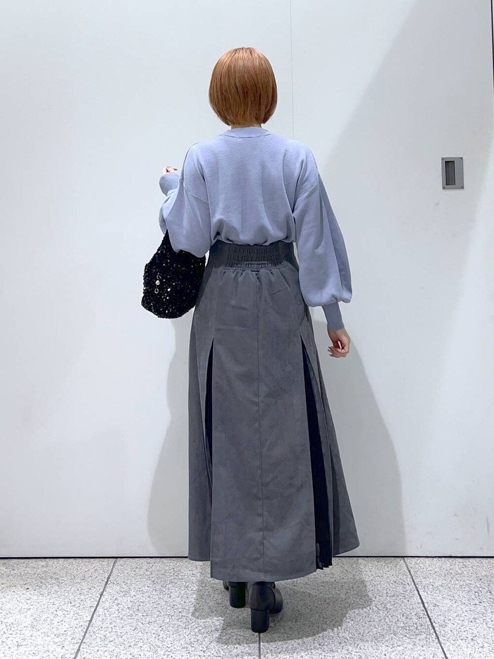 ブラック系のブーツ、ブルー系のニット/セーター、ブラック系のハンドバッグを着用したレディースの冬コーディネートの3枚目の写真