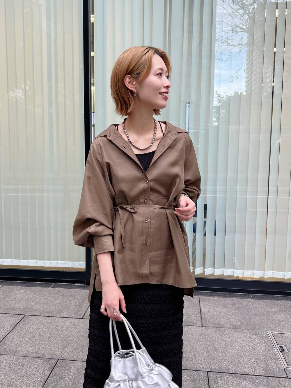 シルバー系のショルダーバッグ、ブラック系のブーツ、ブラック系のスカートを着用したレディースの秋コーディネートの3枚目の写真