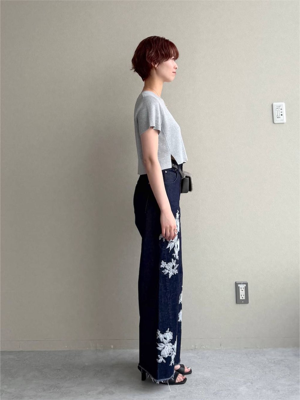 グレー系のニット/セーター、ブルー系のデニムパンツ、ブラック系のサンダルを着用したレディースの夏コーディネートの2枚目の写真