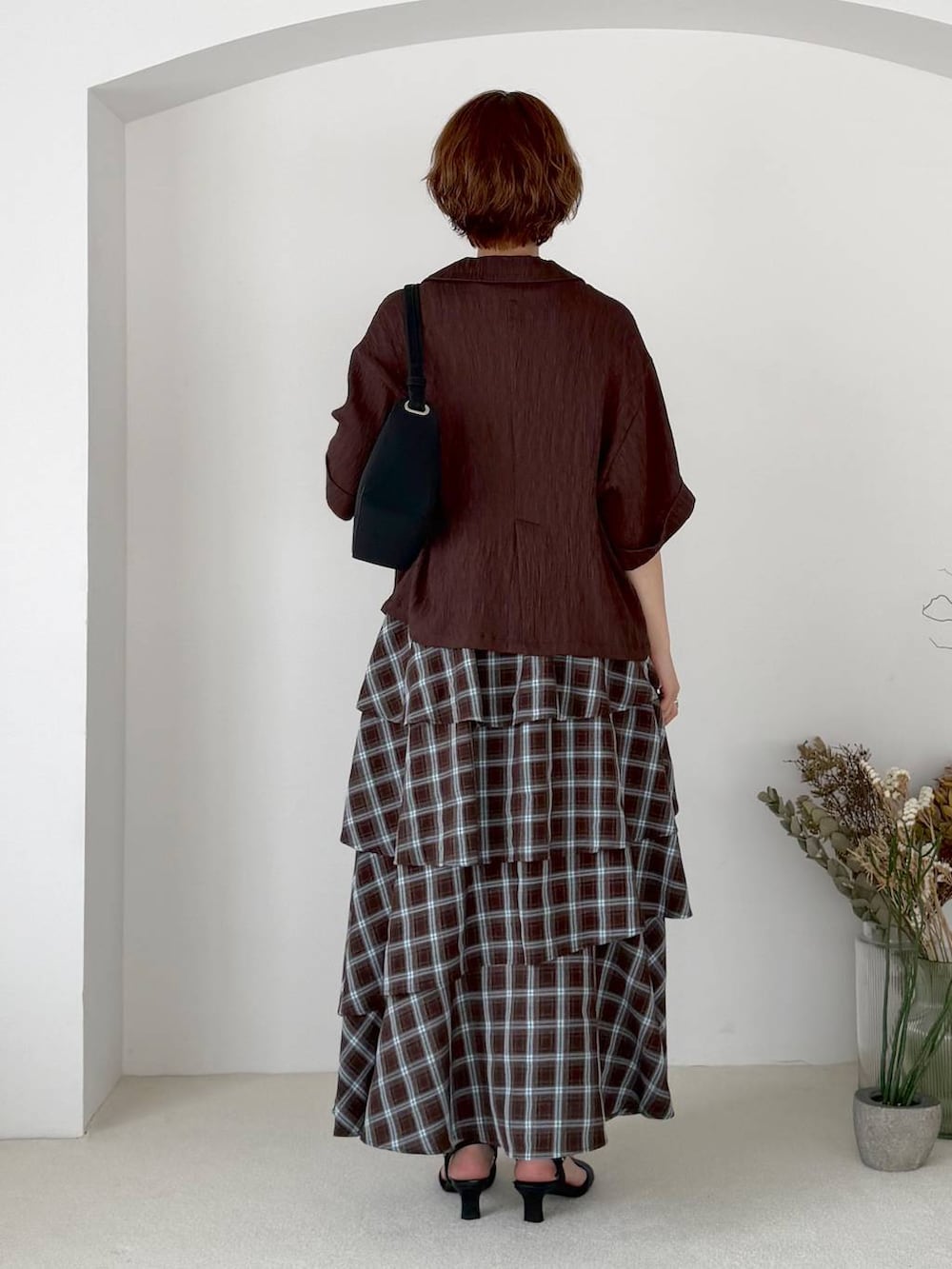 ブラウン系のテーラードジャケット、ブルー系のスカート、ブラック系のTシャツ/カットソーを着用したレディースの夏コーディネートの3枚目の写真