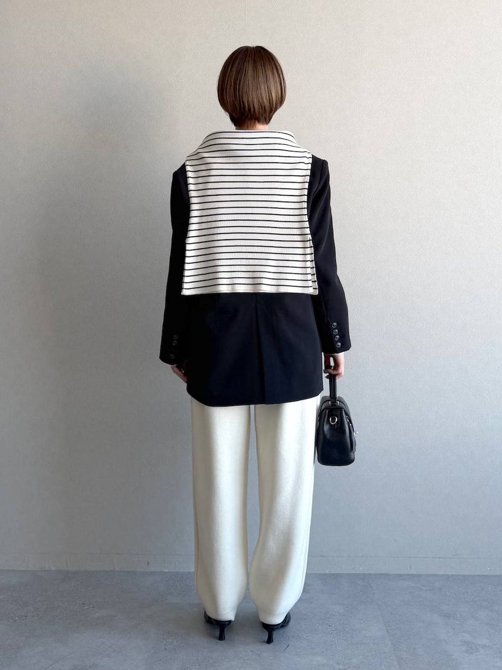 ブラック系のショルダーバッグ、ブラック系のサンダル、グレー系のニット/セーターを着用したレディースの冬コーディネートの3枚目の写真