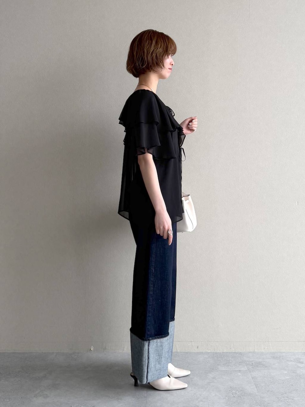 ホワイト系のサンダル、ブルー系のデニムパンツ、ブラック系のシャツ/ブラウスを着用したレディースの春コーディネートの2枚目の写真