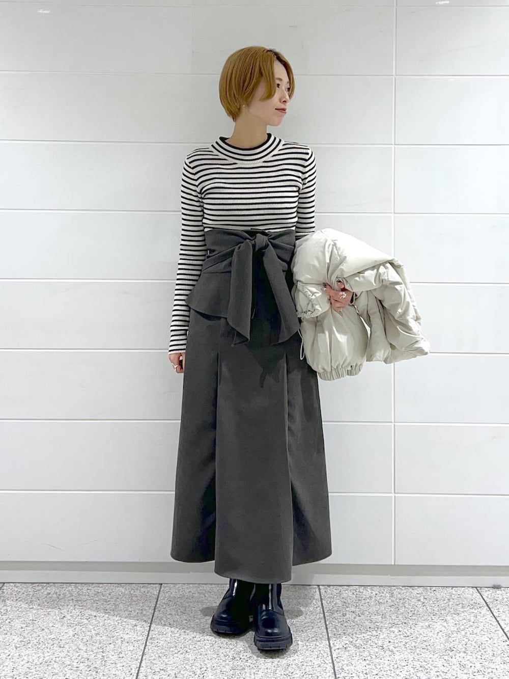 ブラック系のブーツ、ブラック系のニット/セーター、ホワイト系のブルゾンを着用したレディースの冬コーディネートの7枚目の写真