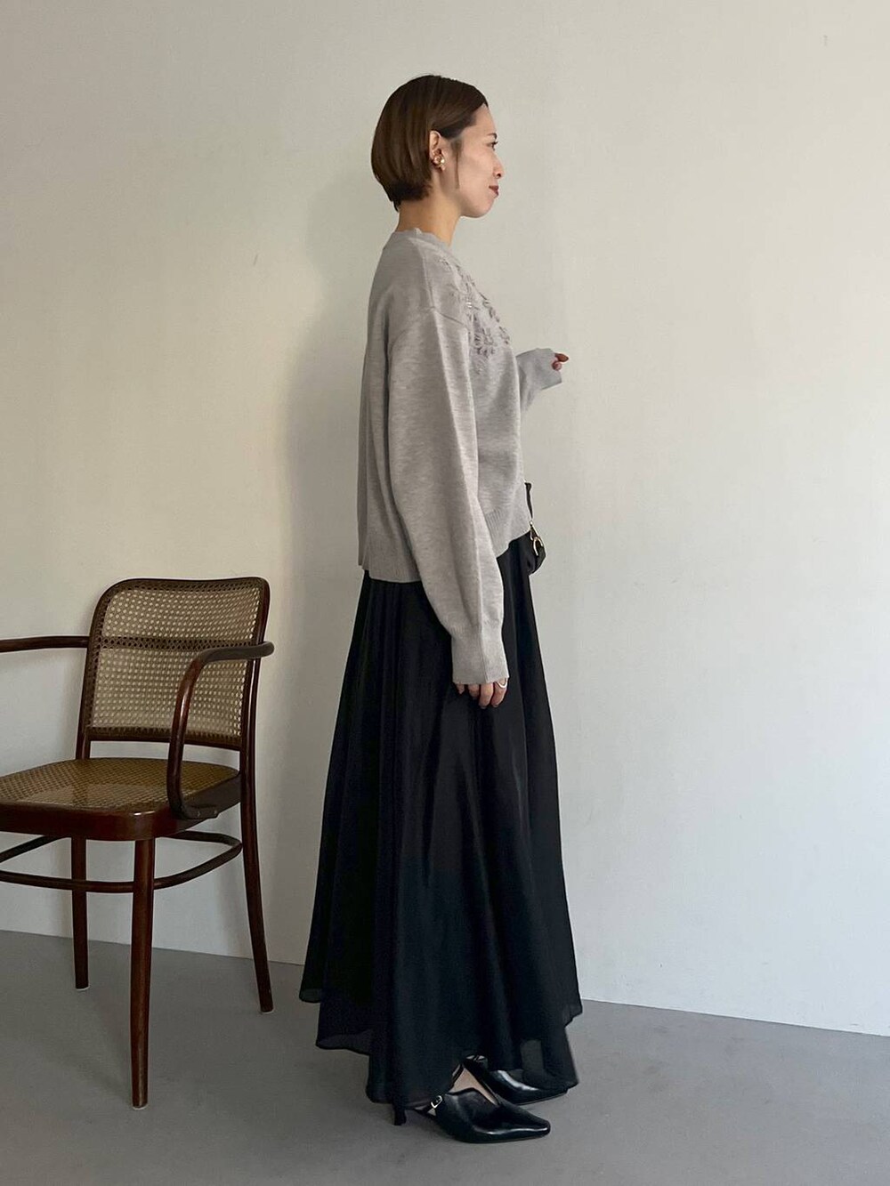 ブラック系のボストンバッグ、ブラック系のサンダル、グレー系のニット/セーターを着用したレディースの冬コーディネートの2枚目の写真